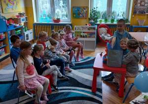 dzieci na widowni z krzesełek oglądają spektakl pokazywany przez dzieci
