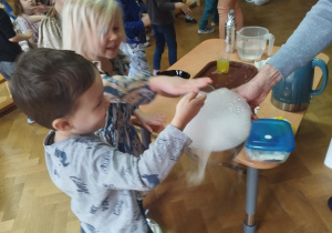 Chłopiec i dziewczynka biorący udział w doświadczeniu z suchym lodem