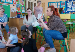 Kobieta z fundacji pokazuje dzieciom książeczkę zdrowia kota.