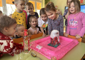 Dzieci oglądają pianę wypływającą z wulkanu.