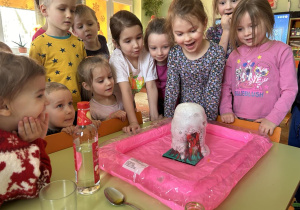 Dzieci oglądają pianę wypływającą z wulkanu.