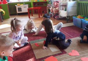 zdjęcie przedstawia dzieci z grupy ,,Misie” segregujące sylwety papierowych serduszek