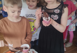 Dziewczynka z chłopcem podczas nakładania surowego ciasta do foremki.