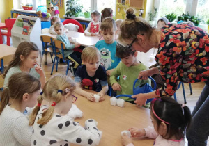 nauczycielka nalewa konewką do pojemniczków z watą wodę