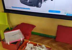 Zawartość apteczki pierwszej pomocy na tle zdjęcia karetki pogotowia