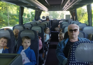 Na zdjęciu widoczne są dzieci siedzące w autokarze.