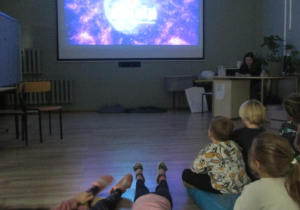 -Dzieci oglądają na tablicy multimedialnej film o układzie słonecznym.