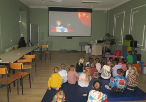 -Dzieci oglądają na tablicy multimedialnej film o układzie słonecznym.