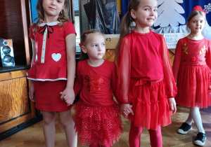 Trzy dziewczynki ubrane na czerwono, pozują do zdjęcia.