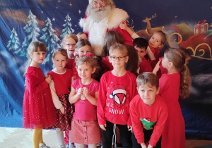 Dzieci pozujące do zdjęcia z Mikołajem.