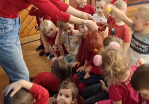 dzieci z gr. II czekają na wylosowanie przez kolegę z ich grupy z woreczka " jajeczka z zagadką", woreczek podaje nauczycielka