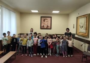 Wspólne zdjęcie Skrzatów na tle fortepianu w sali koncertowej.