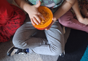 Na zdjęciu dziecko dotyka miąższu i pestek w środku dyni.