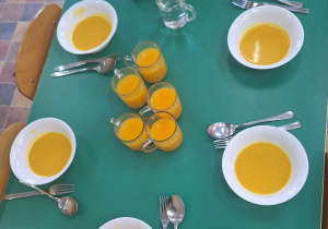 Na zdjęciu jest stół na którym stoją miseczki z zupą dyniową.