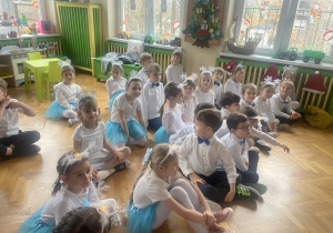 dzieci siedzące na podłodze w oczekiwaniu na rozpoczęcie przedstawienia