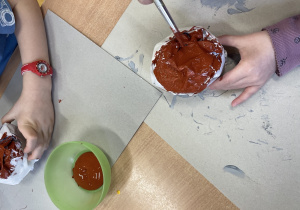 Dzieci malują kulkę z papieru na brązowo