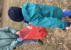 Chłopiec wrzucający śmieci do czerwonego worka