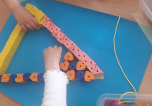 Na zdjęciu dzieci układają z klocków kształt trójkąta.