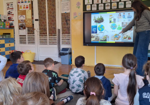 Na zdjęciu dzieci oglądają prezentację multimedialną na temat segregacji odpadów.