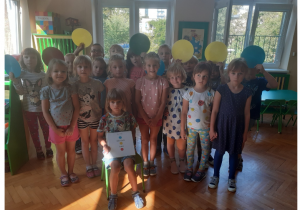 Zdjęcie przedstawia dzieci w sali trzymające kolorowe koła