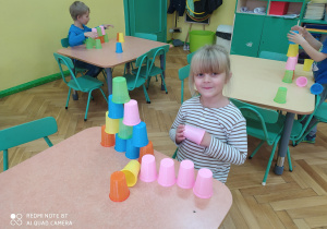 Dziewczynka podczas układania kolorowych kubków wg podanego wzoru