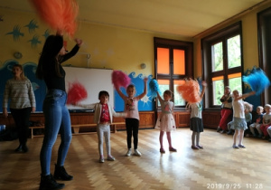 dzieci tańczące z kolorowymi pomponami