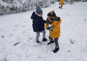 Zdjęcie przedstawia dwóch chłopców bawiących się na śniegu.