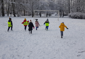 Zdjęcie przedstawia grupę dzieci biegnących na śniegu.