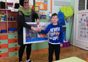 na zdjęciu - chłopiec, któremu składa gratulacje pani Basia i która trzyma w ręce pracę plastyczną Franka, przedstawiającą ilustrację sowy.