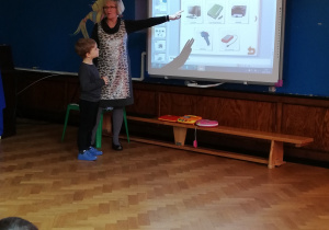 chłopiec z nauczycielką pokazują na tablicy multimedialnej urządzenia elektroniczne