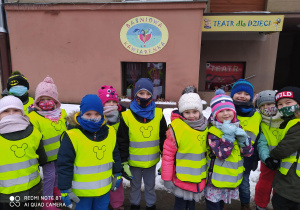 Dzieci z grupy czwartej stoją przed teatrem "Baśniowa Kawiarenka" w odblaskowych kamizelkach