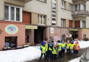 Na zdjęciu grupa dzieci stojąca na ulicy przed wejściem do teatru "Baśniowa Kawiarenka".