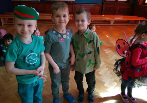 Trzech chłopców ubranych w zielone ubranka z wiosennymi akcentami