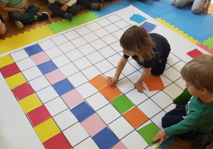 Dzieci układają rytm z kolorowych kartoników na macie do kodowania