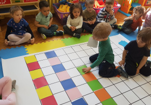 Dzieci układają rytm z kolorowych kartoników na macie do kodowania