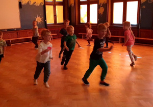 Na zdjęciu dzieci bawiące się w berka na sali gimnastycznej.
