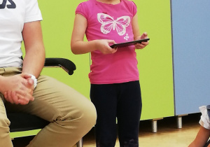 Dziewczynka trzymająca mały tablet, którym steruje robotem