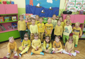 Dzieci z grupy 2 ubrane w żółte stroje pozują do zdjęcia w swojej klasie