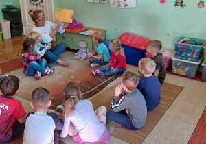 Na zdjęciu: dzieci siedzące na dywanie w klasie oglądają Dzienniczek lektur założony do programu " Mały Miś w świecie wielkiej literatury" dzieci siedzące na dywanie w klasie słuchają nauczycielki czytającej książkę