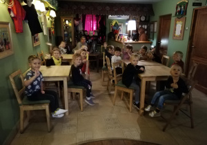 Na zdjęciu: dzieci przy stolikach oglądają rekwizyty na ścianach czekając na przedstawienie