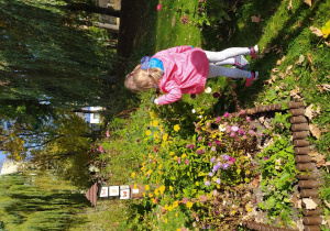 Dziewczynki podczas obserwacji roślin w przedszkolnym ogrodzie przez lupe
