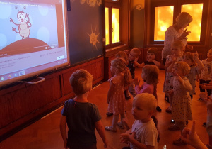 Dzieci tańczą do piosenki o kropkach biedronki, przy na tablicy multimedialnej