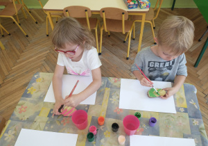 Dziewczynka i chłopiec malują farbami ziemniaki