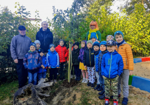 Dzieci z grupy szóstej "Słoneczka" wraz z nauczycielką, Panem Piotrem oraz Panem Maciejem pozują na tle zasadzonego grupowego drzewa