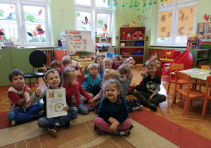 dzieci z gr.IV przed tablicą z ilustracjami o tematyce ekologicznych produktów