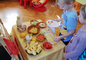 dzieci nakładają sobie po kolei na swoje talerzyki ekologiczne przysmaki z tzw. "szwedzkiego stołu"