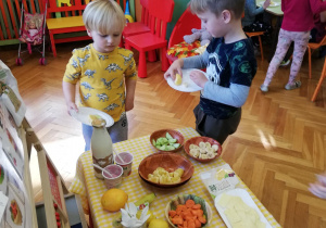 dzieci nakładają sobie po kolei na swoje talerzyki ekologiczne przysmaki z tzw. "szwedzkiego stołu"