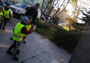 dwóch chłopców stawia znicz pod pomnikiem G. Narutowicza