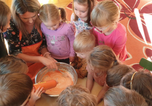 Na zdjęciu dzieci i nauczycielka przygotowujące masę do rosnących farb wykorzystanych w pracy plastycznej.