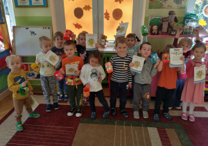 Dzieci z grupy Zajączki pokazują swoje papierowe kubki i Mleczne zeszyty